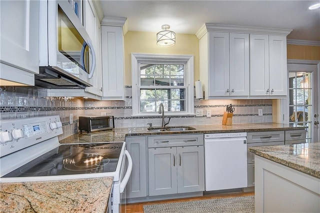 kitchen featuring sink, white appliances, backsplash, light stone countertops, and crown molding