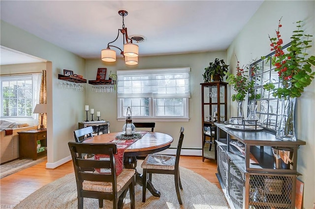 dining area featuring a baseboard heating unit, an inviting chandelier, and light hardwood / wood-style flooring