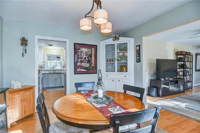 dining area with sink, a chandelier, and light wood-type flooring