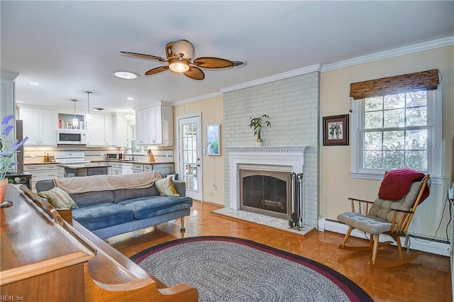 living room featuring light parquet flooring, a brick fireplace, crown molding, ceiling fan, and sink