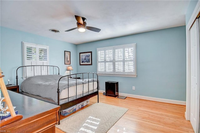 bedroom featuring hardwood / wood-style flooring, ceiling fan, a closet, and multiple windows