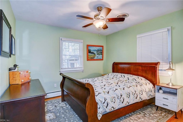 bedroom with ceiling fan, baseboard heating, and hardwood / wood-style floors