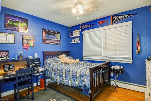 bedroom featuring wood-type flooring, a baseboard heating unit, and ceiling fan