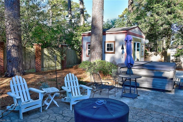 view of patio with a hot tub and an outbuilding