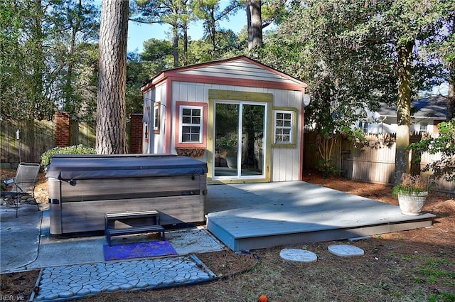 view of patio / terrace with a deck, an outbuilding, and a hot tub