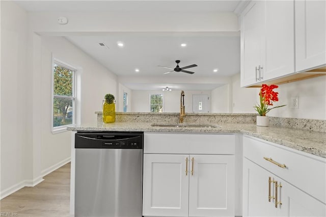 kitchen with light wood-type flooring, light stone counters, sink, white cabinetry, and stainless steel dishwasher