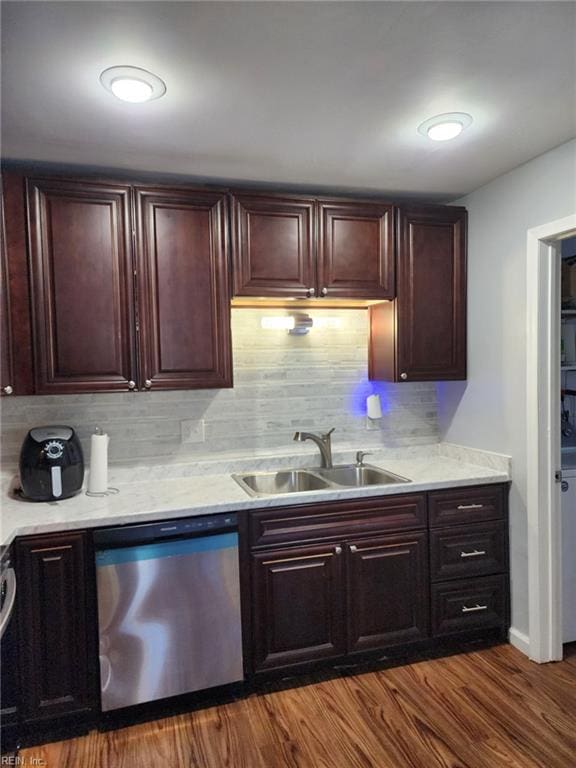 kitchen with hardwood / wood-style floors, stainless steel dishwasher, backsplash, and sink