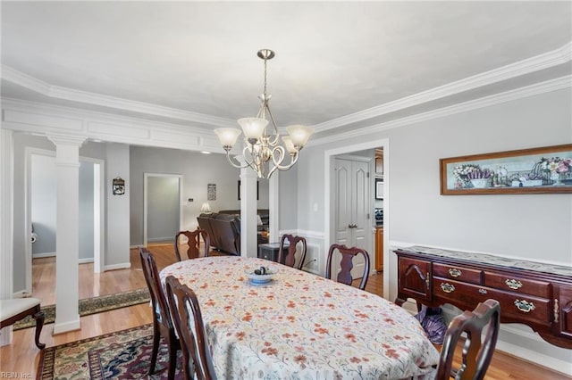 dining area with a notable chandelier, ornamental molding, light hardwood / wood-style floors, and decorative columns