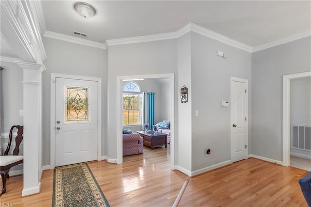 entryway featuring decorative columns, ornamental molding, and hardwood / wood-style floors