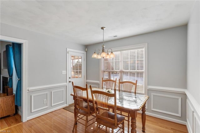 dining space featuring light hardwood / wood-style flooring and a notable chandelier