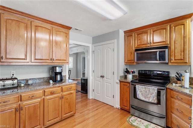 kitchen with light stone counters, stainless steel appliances, and light hardwood / wood-style flooring