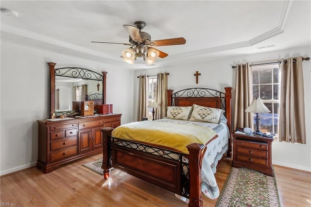 bedroom featuring ceiling fan, a raised ceiling, ornamental molding, and light hardwood / wood-style flooring