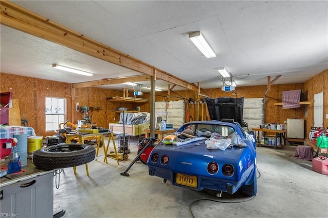 garage with a workshop area, a garage door opener, and wood walls