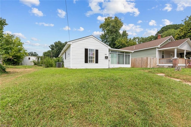 back of property with a sunroom, central AC, and a lawn