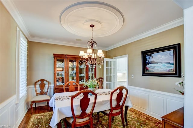 dining area with dark wood-type flooring, crown molding, and a chandelier