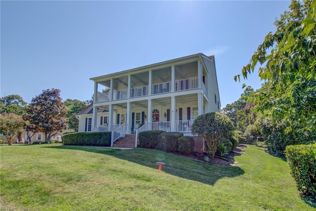 view of front of house with ceiling fan, covered porch, a balcony, and a front lawn