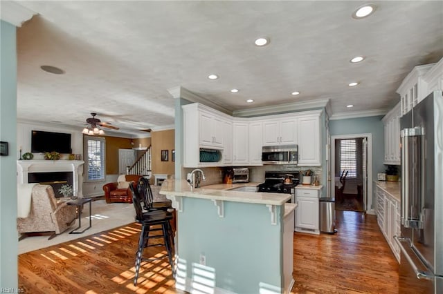 kitchen with stainless steel appliances, kitchen peninsula, a breakfast bar, plenty of natural light, and white cabinetry