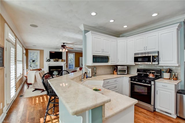 kitchen featuring ornamental molding, kitchen peninsula, gas range, and a breakfast bar area