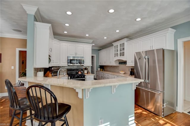 kitchen featuring stainless steel appliances, white cabinets, tasteful backsplash, kitchen peninsula, and a breakfast bar