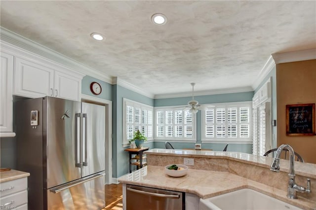 kitchen featuring decorative light fixtures, white cabinets, appliances with stainless steel finishes, ornamental molding, and sink