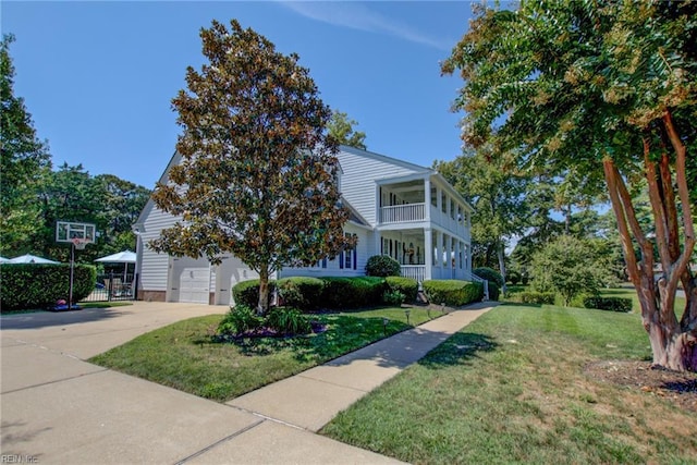 view of front facade featuring a balcony, a front lawn, and a garage