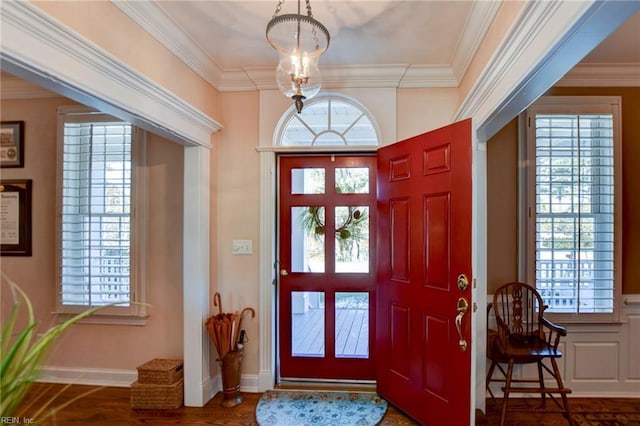 foyer entrance with wood-type flooring, an inviting chandelier, and crown molding