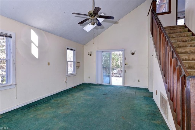 unfurnished living room featuring a wealth of natural light, high vaulted ceiling, ceiling fan, and dark carpet