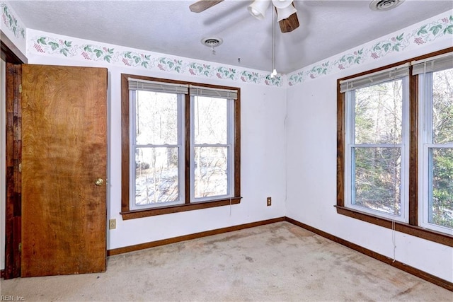 spare room featuring light colored carpet, ceiling fan, and plenty of natural light