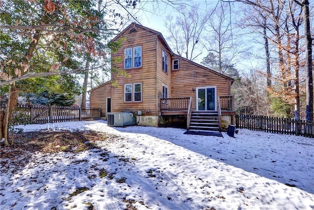 snow covered back of property featuring central AC and a deck