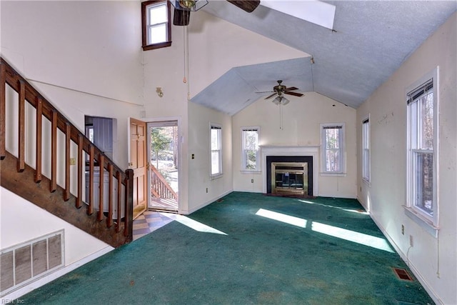 unfurnished living room featuring ceiling fan, a wealth of natural light, carpet, and a textured ceiling