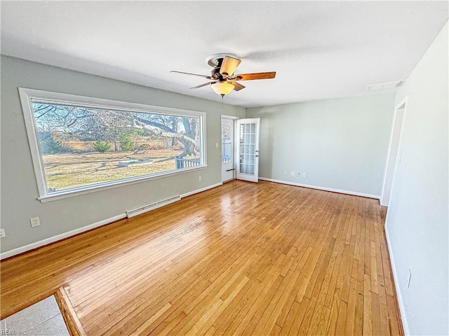 spare room featuring ceiling fan, light hardwood / wood-style flooring, and a baseboard heating unit