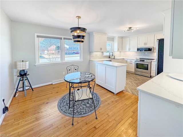 kitchen featuring decorative backsplash, appliances with stainless steel finishes, sink, white cabinetry, and hanging light fixtures