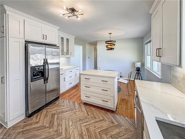 kitchen featuring hanging light fixtures, white cabinets, and stainless steel appliances