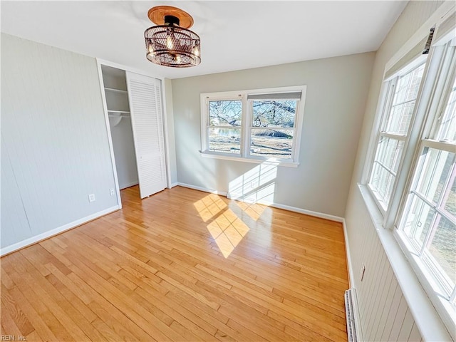 interior space featuring baseboard heating, multiple windows, and light wood-type flooring