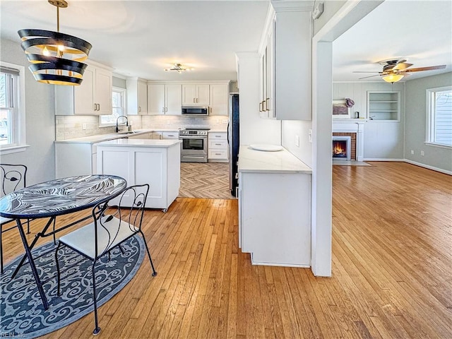 kitchen featuring ceiling fan, sink, light hardwood / wood-style flooring, white cabinets, and appliances with stainless steel finishes