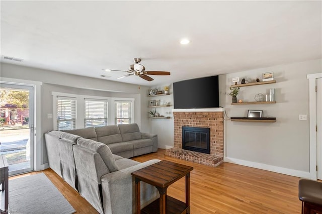 living room with a fireplace, light wood-type flooring, and plenty of natural light