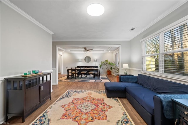 living room with light hardwood / wood-style floors, ornamental molding, and ceiling fan