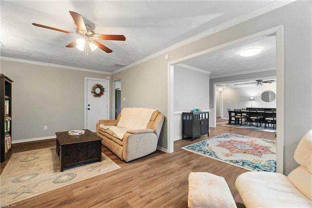 living room featuring light hardwood / wood-style floors, ceiling fan, and crown molding