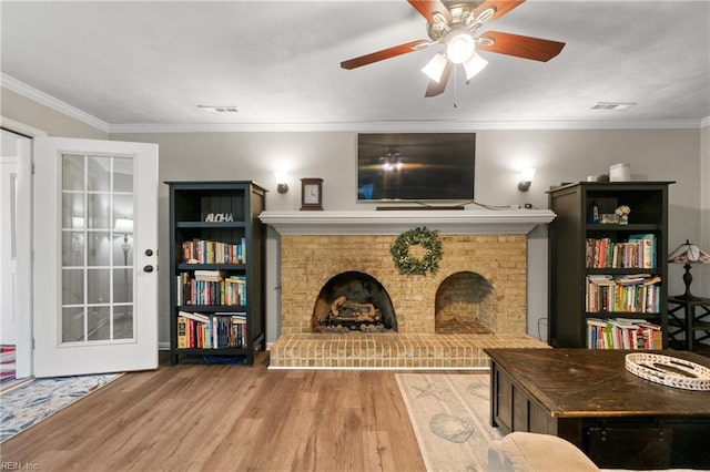 living room with a brick fireplace, ornamental molding, and wood-type flooring