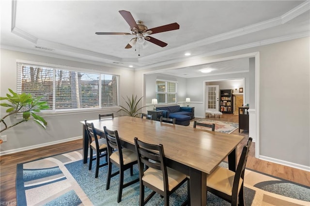 dining area featuring crown molding, hardwood / wood-style flooring, and a tray ceiling