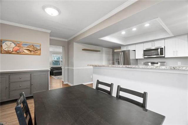 dining space featuring light hardwood / wood-style flooring, crown molding, and a tray ceiling