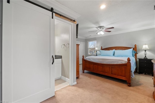 carpeted bedroom featuring ornamental molding, ceiling fan, and a barn door