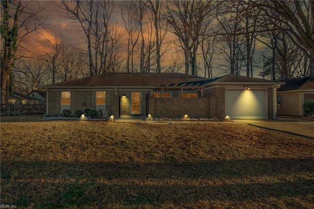 ranch-style house with a garage and a lawn