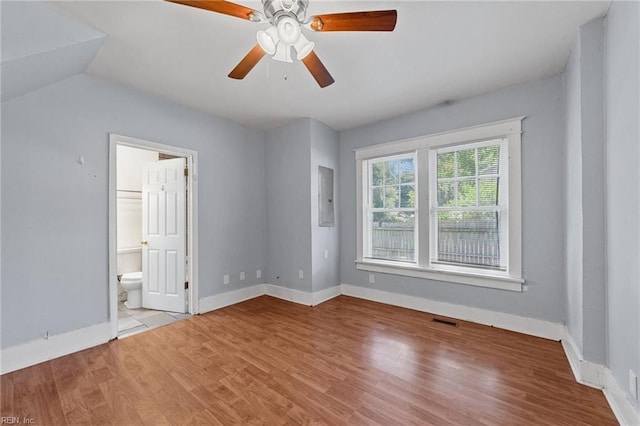 unfurnished bedroom with electric panel, vaulted ceiling, ceiling fan, light wood-type flooring, and connected bathroom