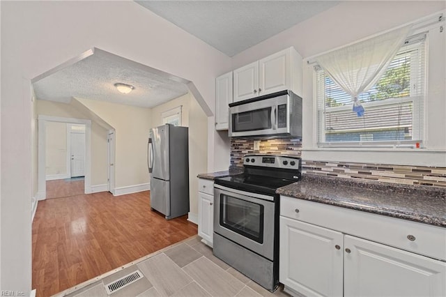 kitchen featuring tasteful backsplash, white cabinets, stainless steel appliances, and a textured ceiling