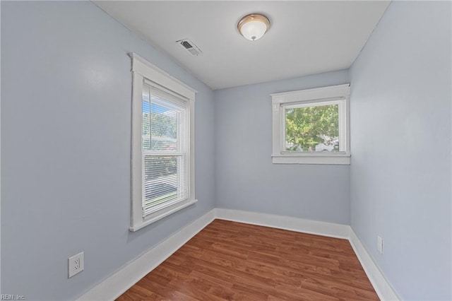 empty room with hardwood / wood-style flooring and a healthy amount of sunlight