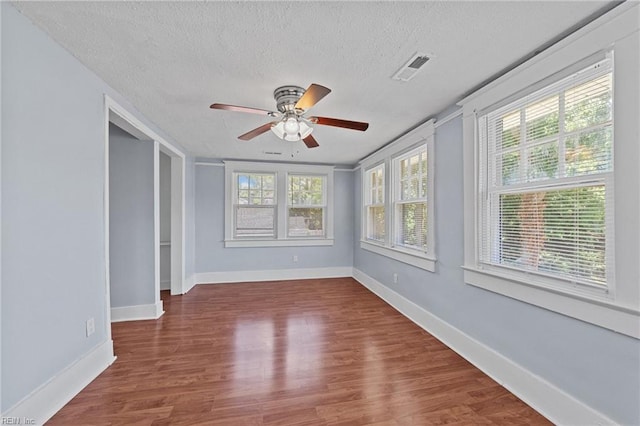 spare room featuring ceiling fan, dark hardwood / wood-style flooring, a textured ceiling, and a wealth of natural light