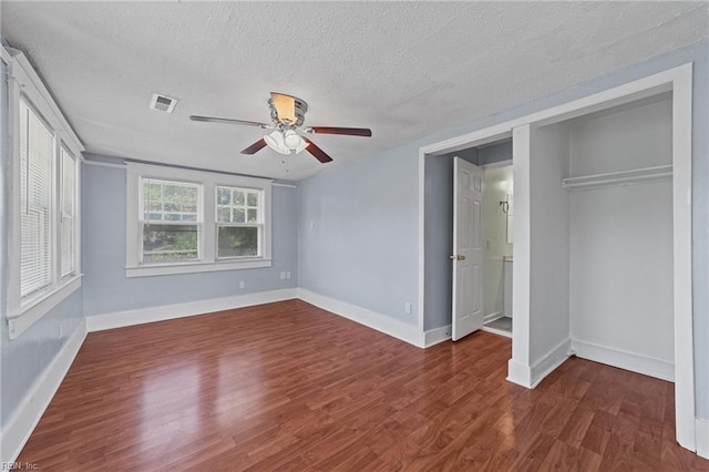 unfurnished bedroom featuring a closet, ceiling fan, dark hardwood / wood-style flooring, and a textured ceiling