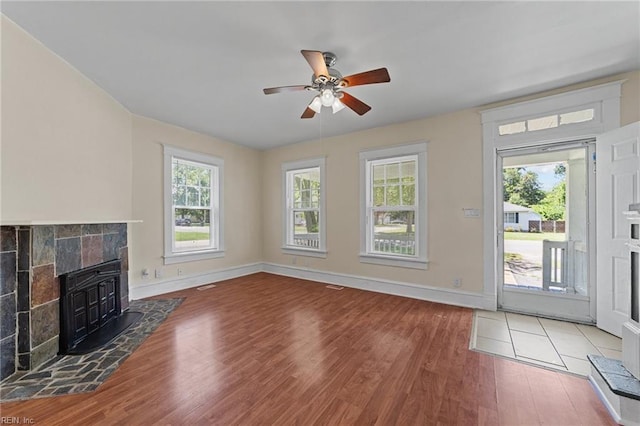 unfurnished living room featuring dark hardwood / wood-style flooring, ceiling fan, and a fireplace