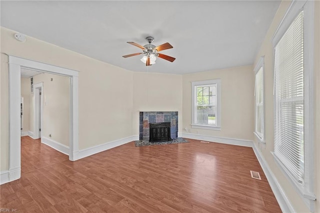 unfurnished living room featuring a tile fireplace, wood-type flooring, and ceiling fan